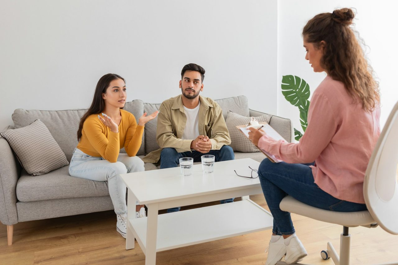 Couple in therapy session with counselor woman